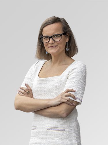 A portrait of Katarina Ceglar, Deputy Head of Tourism 4.0. She is a middle-aged woman with long brown hair, wearing glasses and a white dress, smiling.