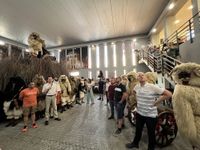 Fotografija, posneta na sestanku upravnega odbora, kjer obiskovalci občudujejo bušose (tradicionalne madžarske maske).