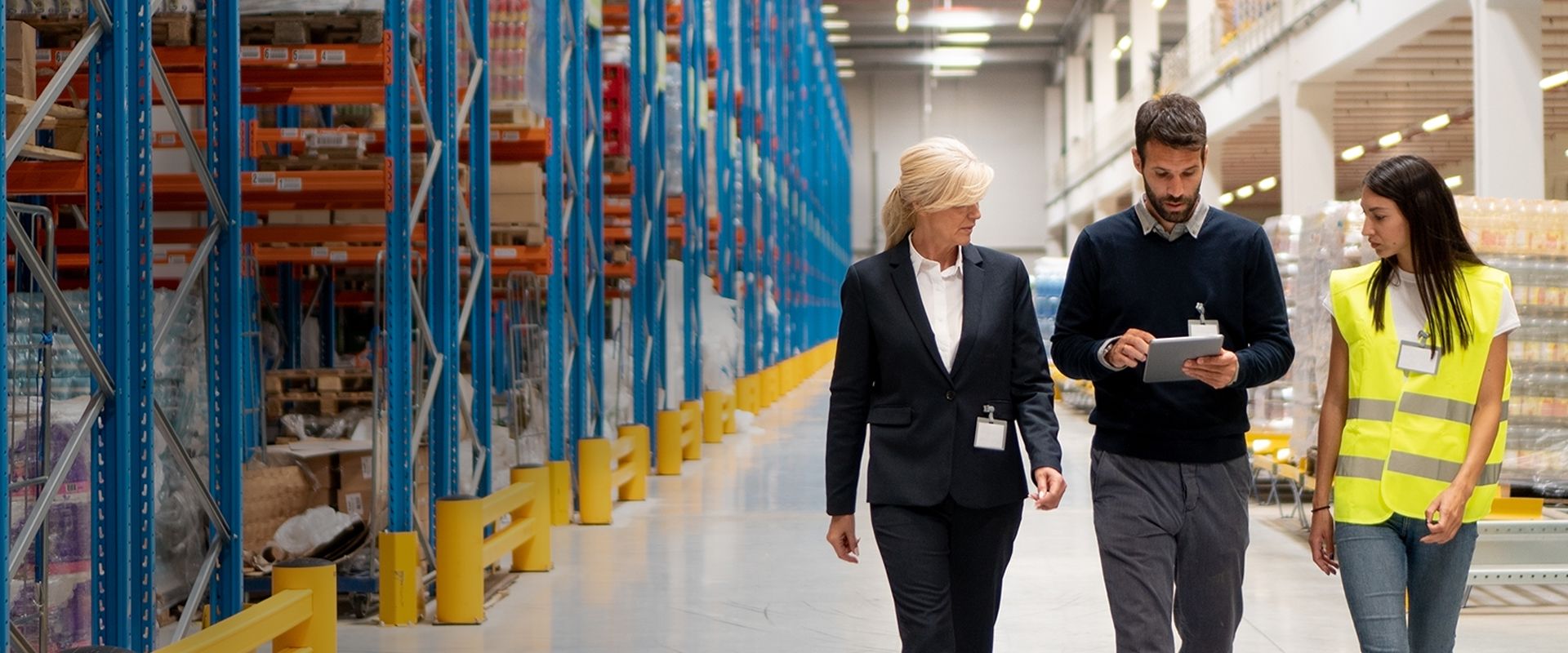 Three employees are walking through a warehouse.