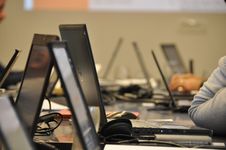 Photograph of listeners sitting behind the table, attentively listening at the precentor and writing notes on the laptops.