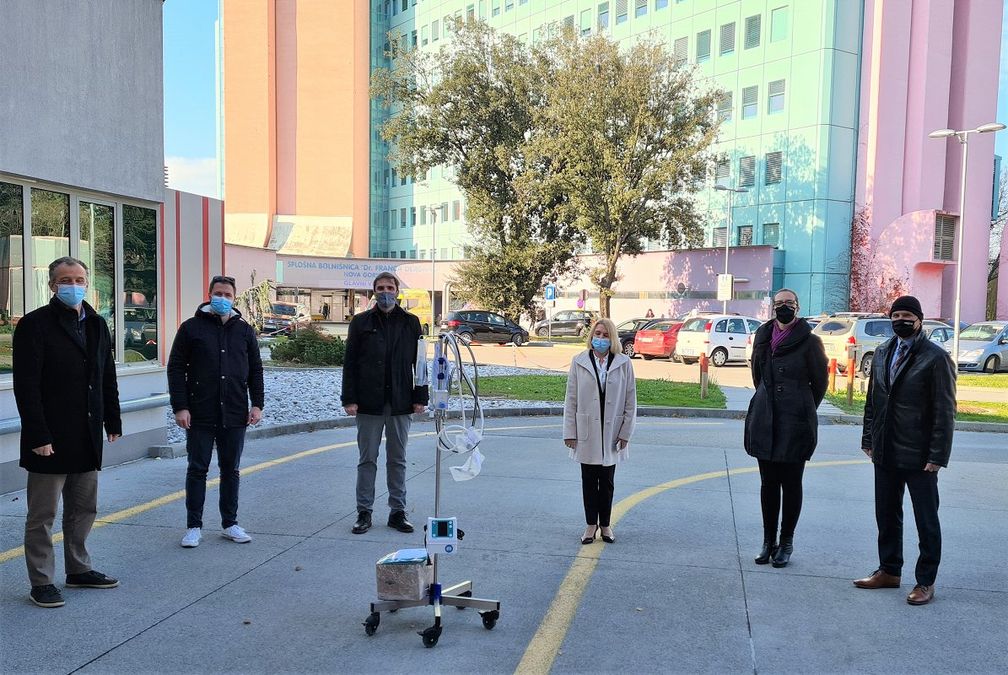 Skupinska fotografija šestih ljudi (med njimi sta generalni direktor in ustanovitelj podjetja Arctur ter izvršni direktor podjetja Arctur) pred Splošno bolnišnico v Novi Gorici.