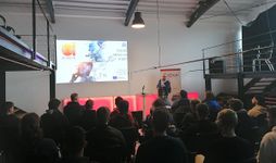An Arctur employee is delivering a presentation titled 'AI-powered Next generation of VET' in front of the audience.