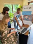 Photo of a woman and two boys looking at Reginna 4.0 fliers. In front of them is an interactive display screen.