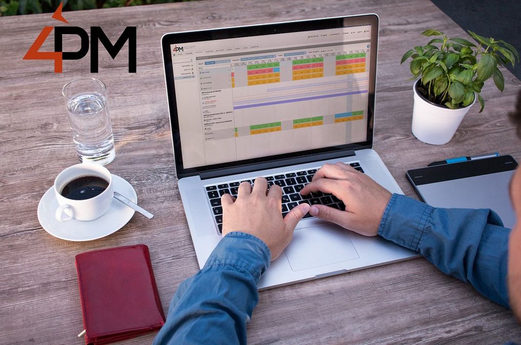 A photograph of a man using the 4PM application on a laptop. To the left of the laptop, there is a cup of black coffee, a glass of water, a small notepad, a digital tablet, and a green plant.