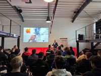 An Arctur employee is delivering a presentation titled 'AI-powered Next generation of VET' in front of the audience.