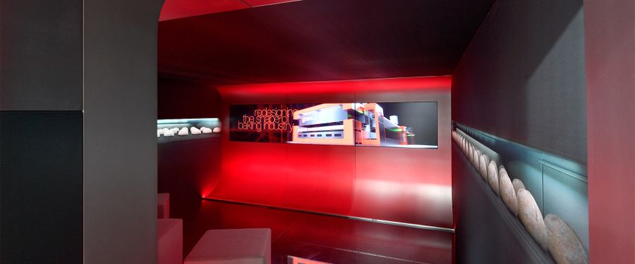 A dark red room with a poster saying 'Redesigning the shape of the baking industry.'