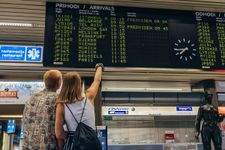 Photograph of two tourist looking at departure and arrival board at the airport.