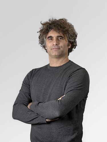 Portrait photograph of Tristian Pahor, Head of department HPC & DC. He is a middle-aged man with curly brown hair, wearing dark grey shirt, smiling.